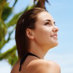 Woman looking up toward the sun with palm trees behind her — Ceteareth-20 emulsifier used in ORY Skincare formulations.