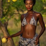onfident woman with natural afro holding fresh marula fruit in lush marula tree grove, illustrating the antioxidant-rich Marula Oil in Oryskincare's hydrating skincare products for nourished, youthful, and glowing skin.