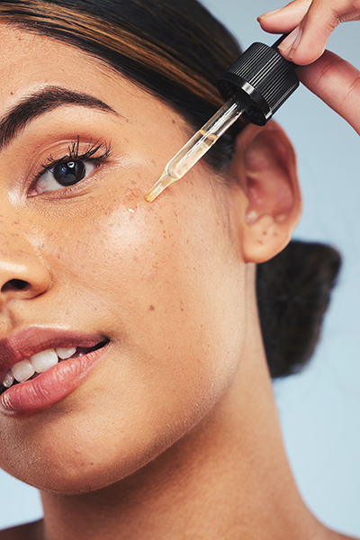 Close-up of woman applying facial oil with dropper — hydrating botanical serum by ORY Skincare.