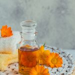 Bottle of calendula-infused oil surrounded by fresh calendula flowers — natural soothing skincare ingredient for ORY Skincare.