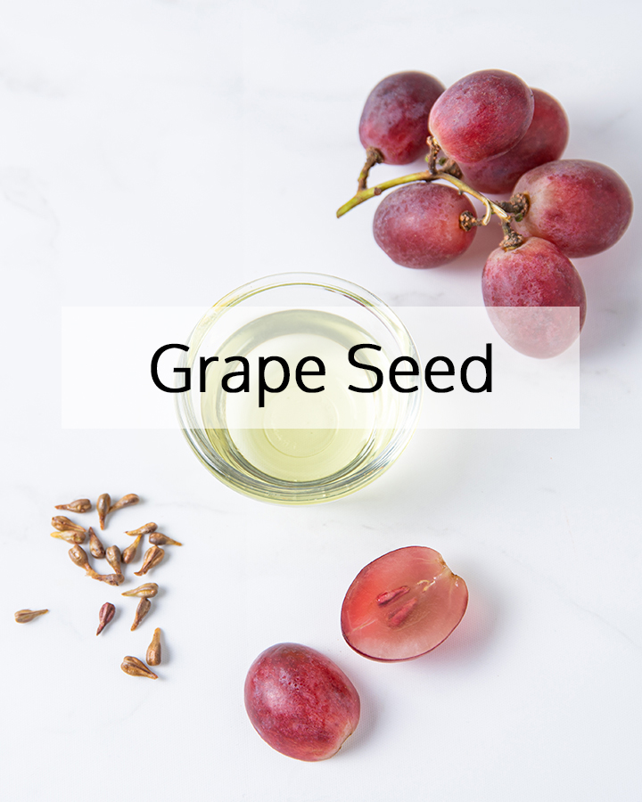 Grape seed oil in a glass bowl surrounded by fresh grapes and grape seeds, representing ORY Skincare’s use of grape seed as a lightweight, antioxidant-rich botanical ingredient for skin balance and protection.