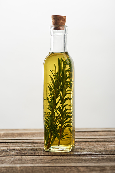 rosemary_infused_oil Rosemary infused oil in a clear glass bottle, showcasing fresh rosemary sprigs suspended in golden botanical oil for natural skincare formulation.