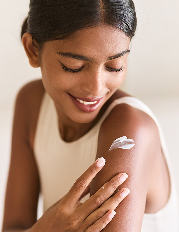 Woman gently applying moisturizing cream to her arm during a nourishing ORY Skincare daily skincare routine.