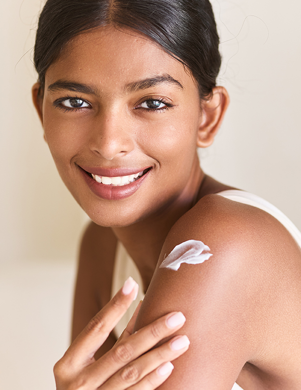 Woman applying moisturizing cream to her shoulder as part of a daily skincare routine, highlighting smooth, nourished skin with ORY Skincare.