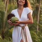 Woman standing in a tropical setting holding coconut and palm fruit, representing ORY Skincare’s use of sodium lauryl glucose carboxylate, a gentle plant-derived surfactant used for mild cleansing and skin comfort.