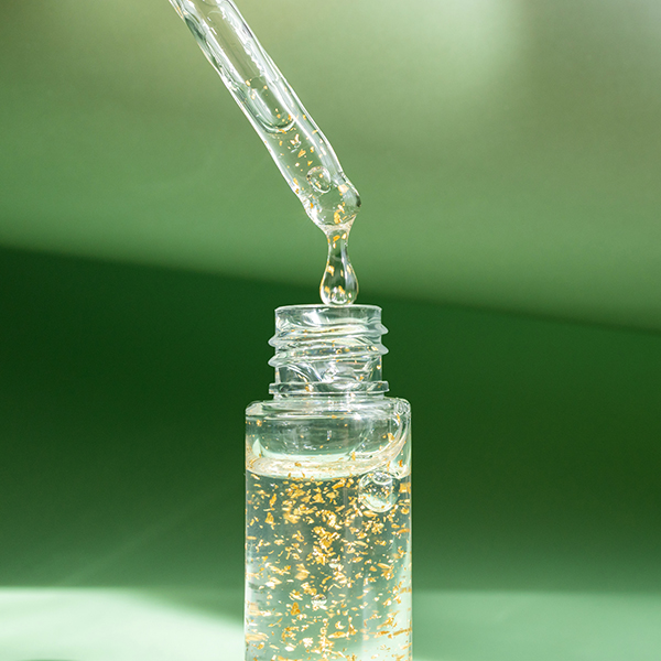 Bi-phasic skincare infusion with botanical extracts suspended in a clear serum, demonstrating oil-and-water phase technology for targeted skin nourishment