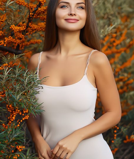 Woman standing among sea buckthorn berries and foliage, representing sea buckthorn seed oil used in ORY Skincare for antioxidant-rich, skin-repairing botanical formulations.